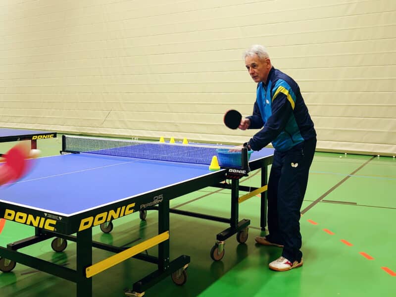 Der Trainer des TTC Mellrichstadt e.V. spielt einer Spielerin Tischtennisbälle zu auf einer Tischtennisplatte.